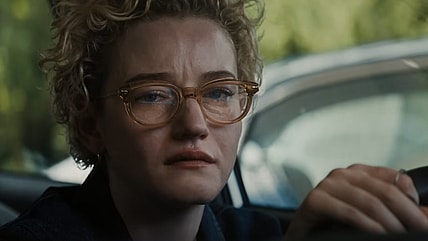 Weapons Julia Garner Woman with glasses and short blonde, curly hair crying with her hands on the steering wheel