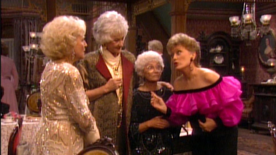 A still from The Golden Girls with (left to right) Betty White, Bea Arthur, Estelle Getty and Rue McClanahan standing together in a Victorian-esque mansion