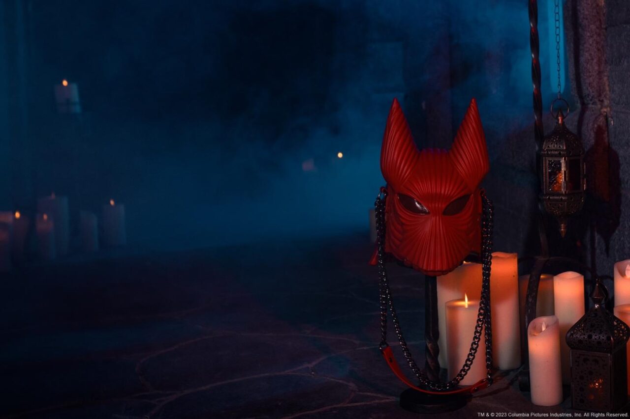 A red mask and candles on a black stand

Description automatically generated